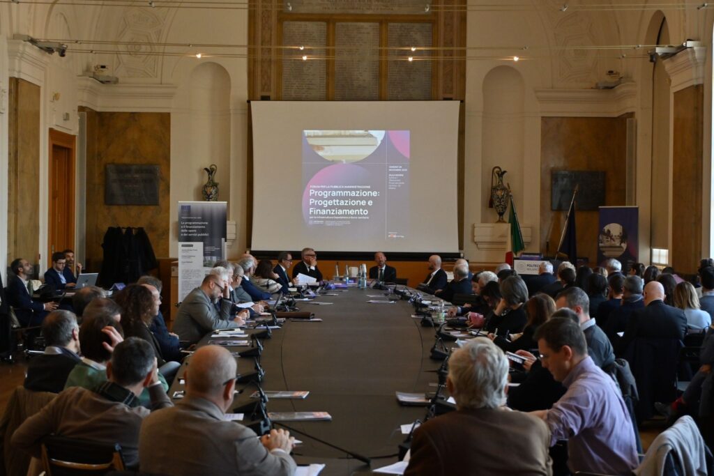 Sala conferenze del Politecnico di Milano con partecipanti al tavolo di lavoro su "Programmazione: Progettazione e Finanziamento per le Infrastrutture Ospedaliere e Socio-Sanitarie", 28 novembre 2025