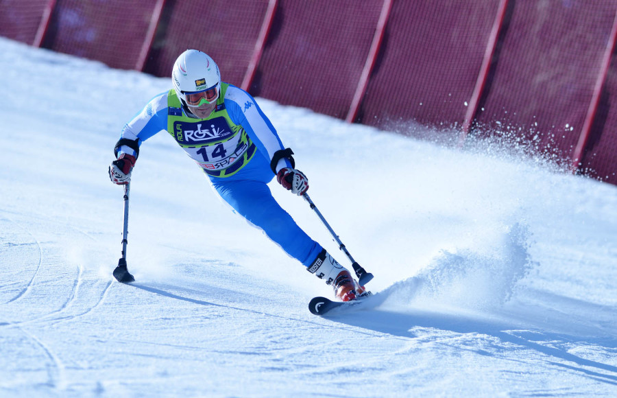 Atleta paralimpico in categoria Standing scia su un pendio con una protesi all'arto inferiore e stabilizzatori