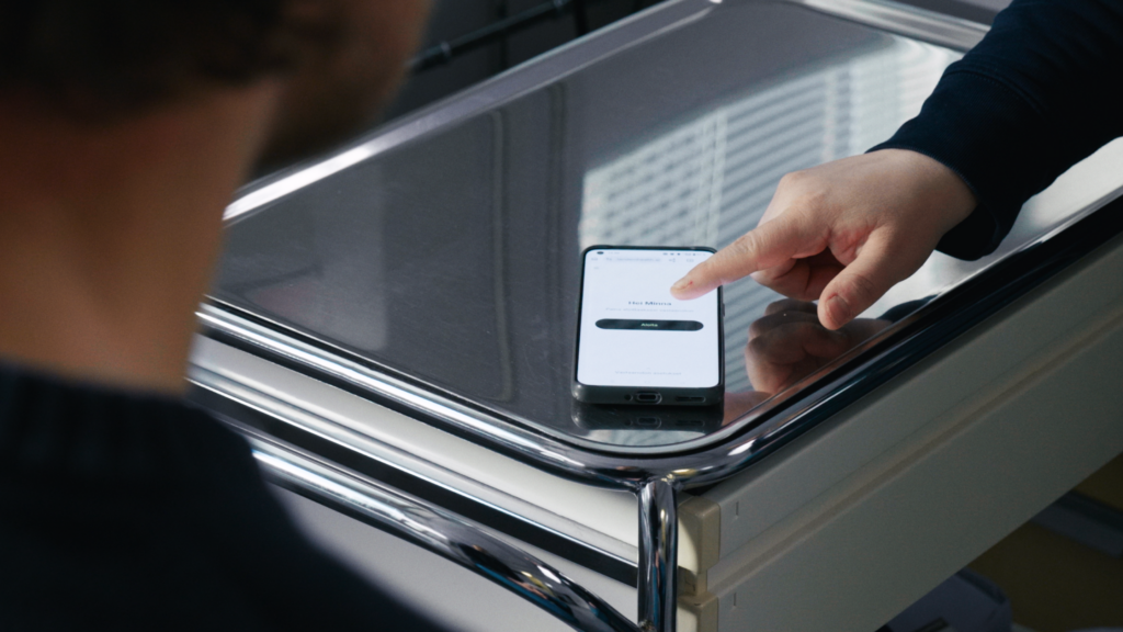 Un operatore clinico interagisce con l'app Tandem Health su uno smartphone appoggiato su un carrello medico